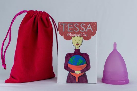 The image shows a purple Tessa menstrual cup alongside its packaging and a red storage bag. The packaging features an illustration of a woman holding a globe.